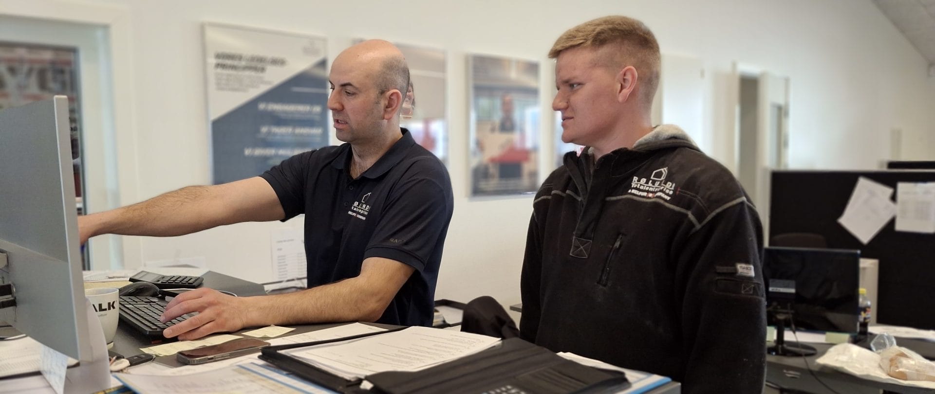 To mænd kigger sammen på en computer på kontoret.