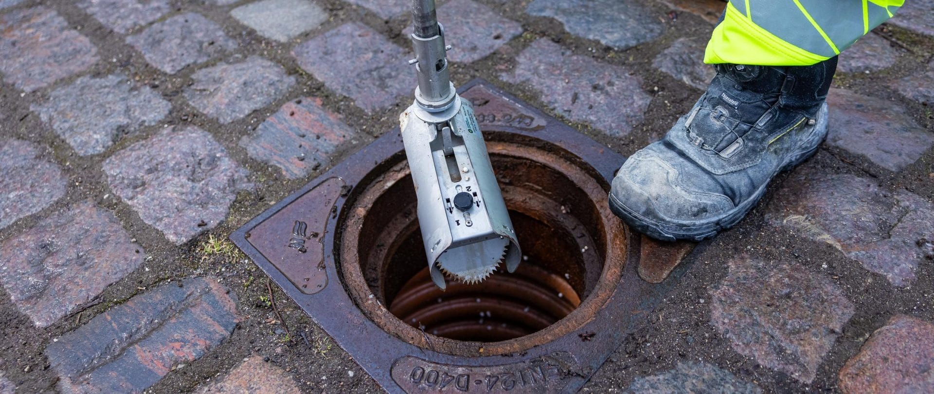 En rottefælde bliver sænket ned i en skakt af en medarbejder.